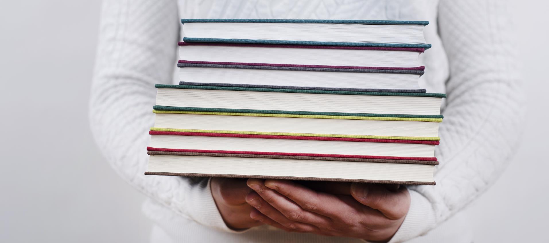 Eine Frau trägt einen Stapel Bücher