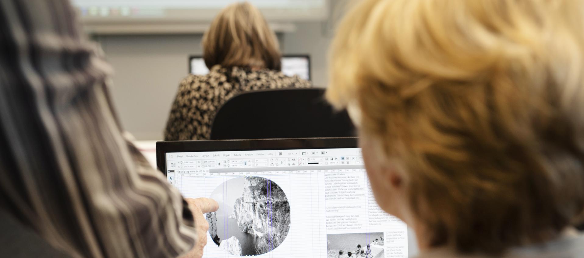 Frau sitzt vor dem Computer und kriegt etwas gezeigt